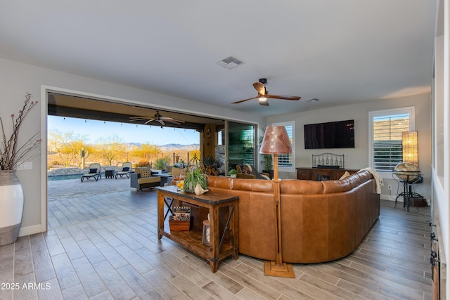 living room with visible vents, light wood-style floors, and a ceiling fan