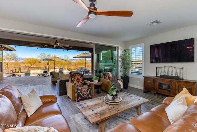 living room featuring visible vents, ceiling fan, and wood finished floors