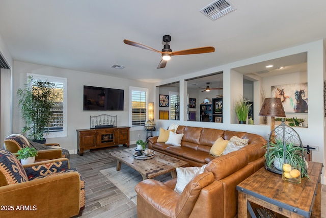 living area featuring visible vents, baseboards, wood finished floors, and a ceiling fan