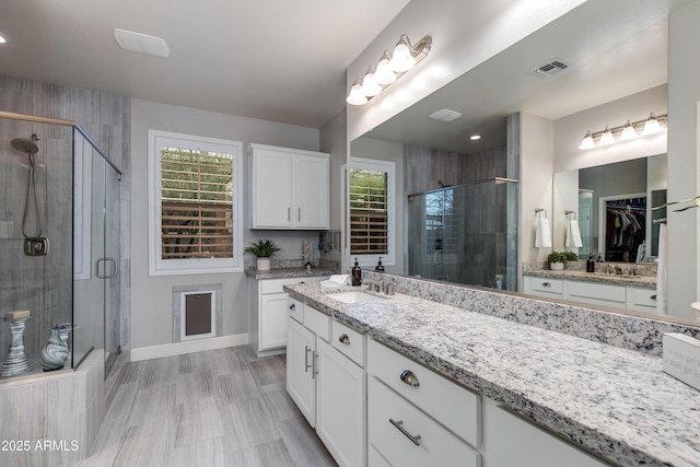 full bathroom featuring visible vents, baseboards, vanity, and a shower stall