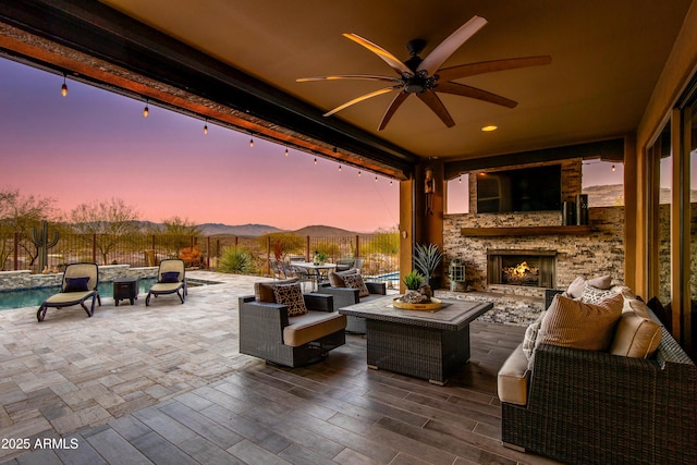 view of patio / terrace with ceiling fan, a fenced backyard, and an outdoor living space with a fireplace