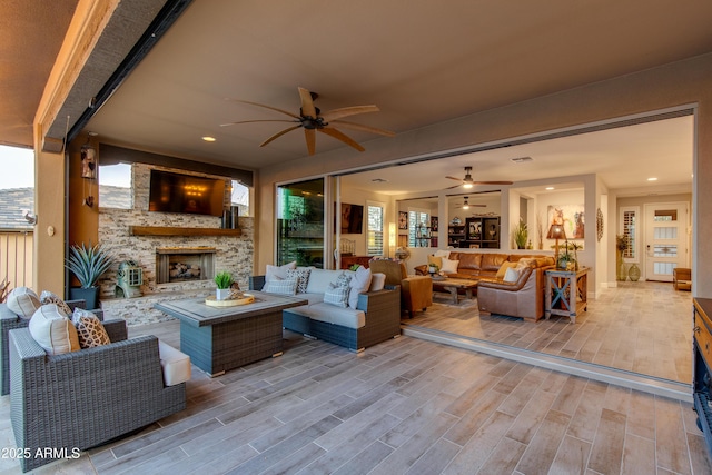 living room featuring recessed lighting, an outdoor stone fireplace, ceiling fan, and wood tiled floor