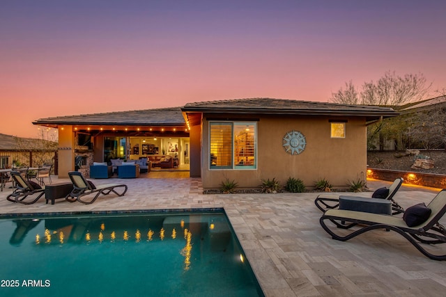 back of property with a patio, stucco siding, an outdoor pool, and an outdoor living space