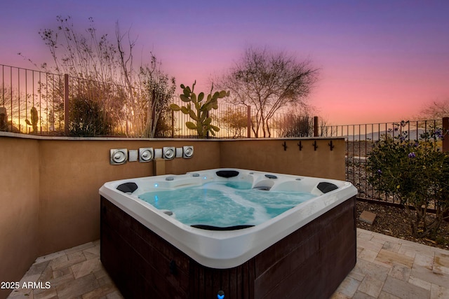 patio terrace at dusk with a hot tub and fence