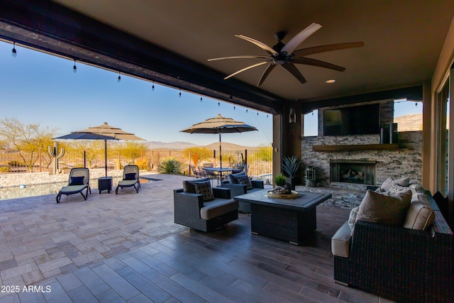 view of patio with outdoor dining area, fence, ceiling fan, and an outdoor living space with a fireplace