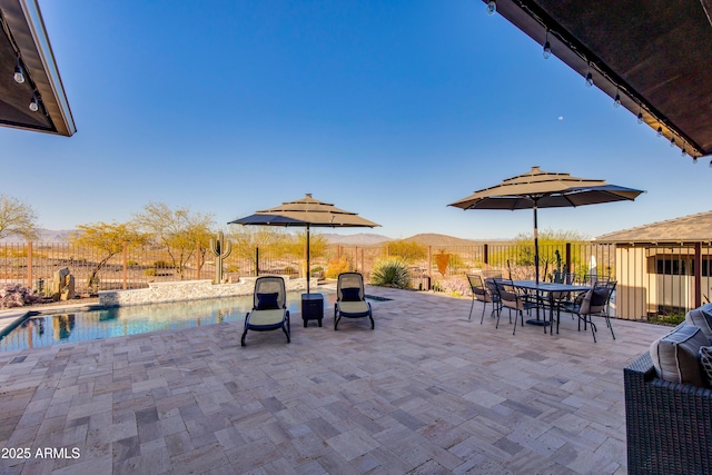 view of patio featuring outdoor dining area, a mountain view, and fence