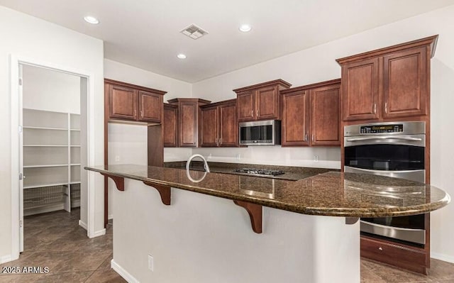 kitchen with sink, appliances with stainless steel finishes, a spacious island, a kitchen bar, and dark stone counters