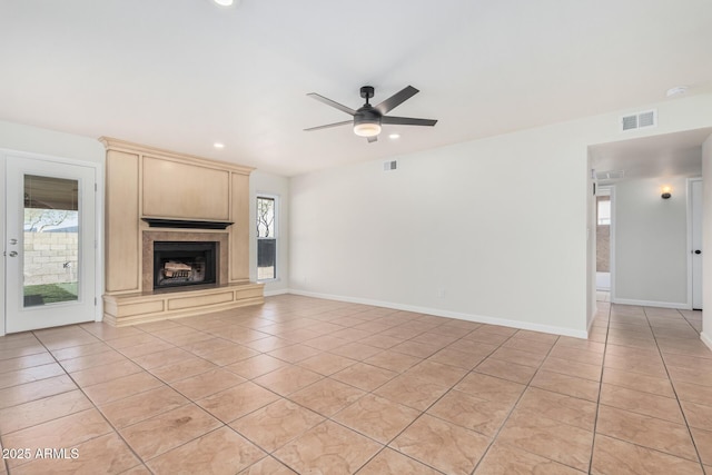 unfurnished living room with ceiling fan, visible vents, a large fireplace, and light tile patterned flooring