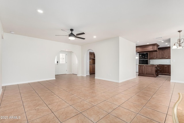 unfurnished living room featuring baseboards, light tile patterned floors, recessed lighting, ceiling fan with notable chandelier, and arched walkways