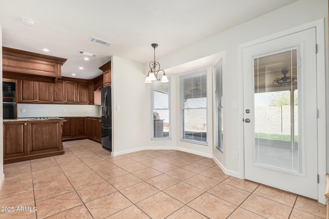 kitchen with baseboards, visible vents, light tile patterned flooring, black appliances, and pendant lighting