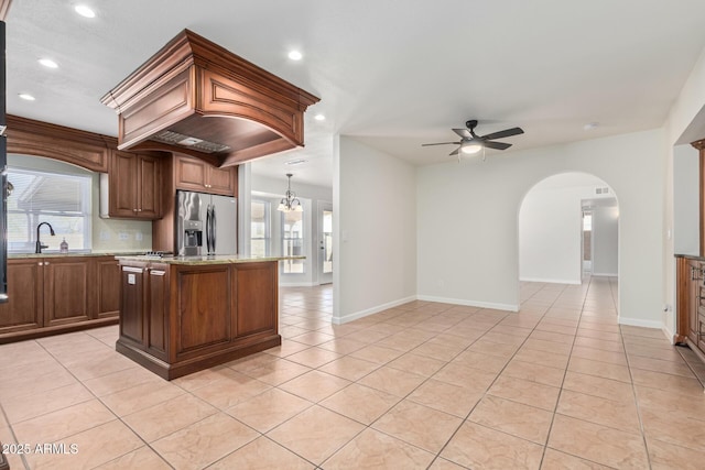 kitchen with a kitchen island, light tile patterned floors, decorative backsplash, stainless steel fridge, and a ceiling fan