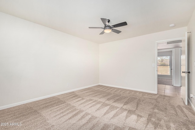 carpeted spare room with a ceiling fan, baseboards, visible vents, and tile patterned flooring