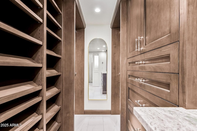 spacious closet with arched walkways and marble finish floor