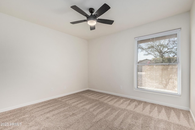 carpeted spare room with ceiling fan and baseboards