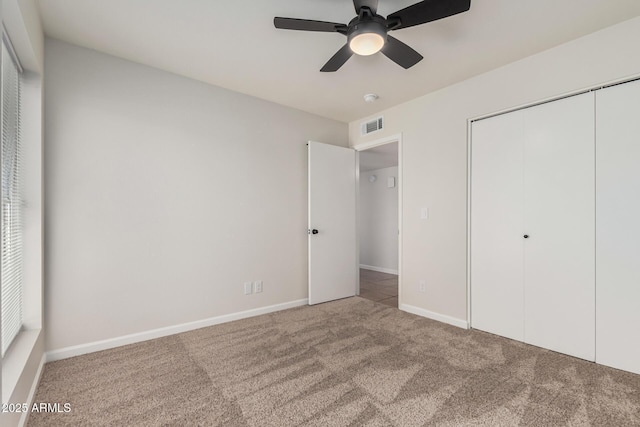 unfurnished bedroom featuring visible vents, a closet, carpet flooring, baseboards, and ceiling fan