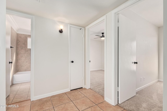 hall with light tile patterned floors, baseboards, and light carpet