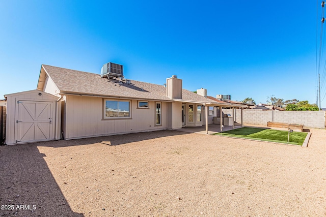 back of house with a patio, cooling unit, a fenced backyard, and an outbuilding