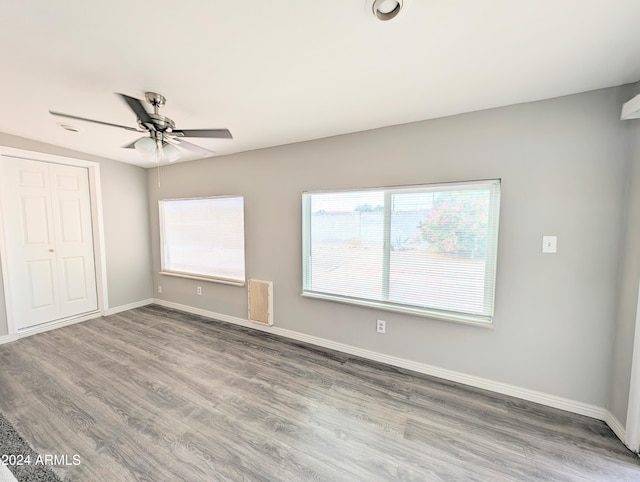 unfurnished bedroom featuring a closet, multiple windows, hardwood / wood-style flooring, and ceiling fan