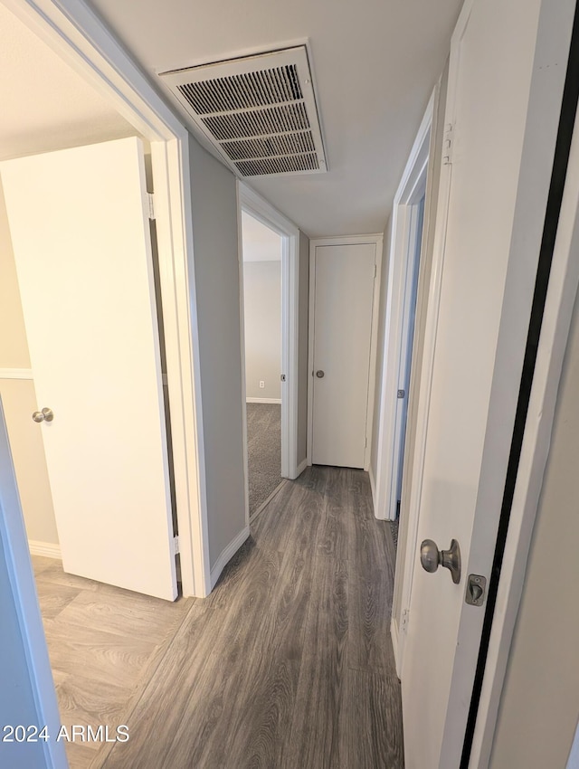 hallway featuring wood finished floors, visible vents, and baseboards