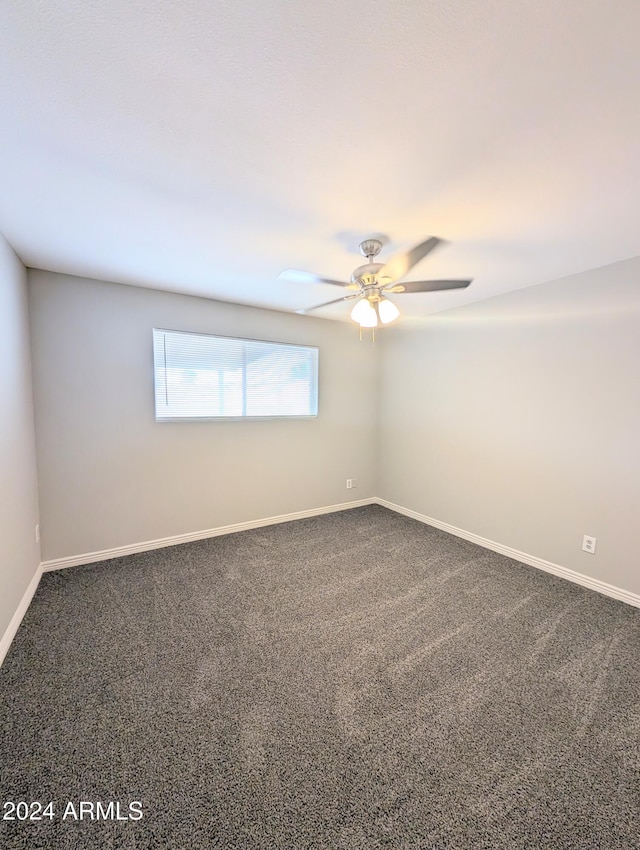empty room featuring a ceiling fan, dark colored carpet, and baseboards