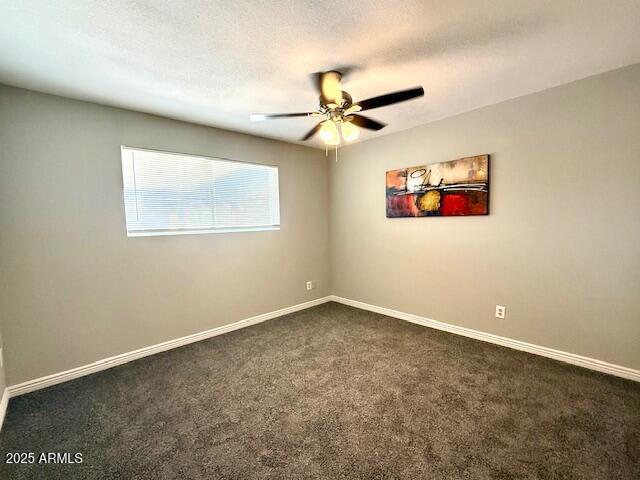 unfurnished room with dark carpet, a ceiling fan, and baseboards