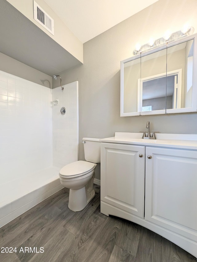 bathroom featuring tiled shower, vanity, toilet, visible vents, and wood finished floors