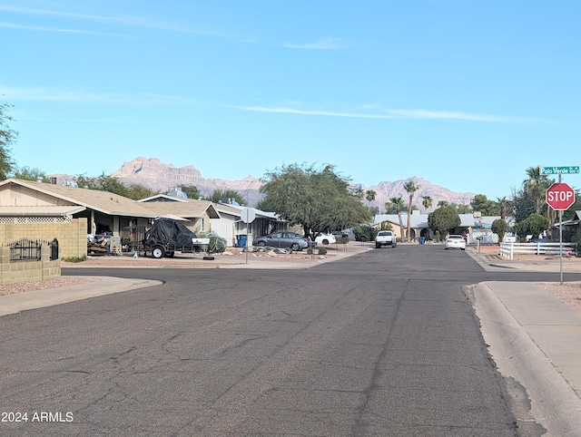 view of street with traffic signs, curbs, a residential view, sidewalks, and a mountain view