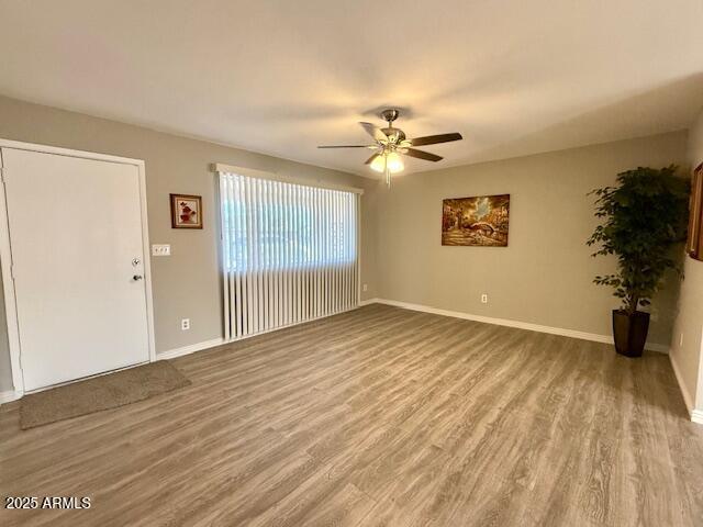 spare room with a ceiling fan, wood finished floors, and baseboards