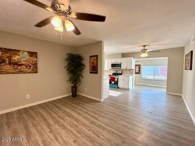unfurnished living room featuring visible vents, a ceiling fan, and baseboards