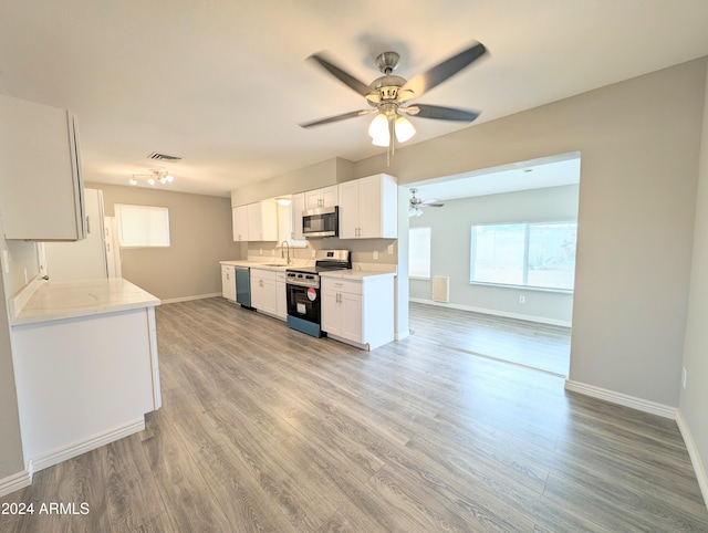 kitchen featuring white cabinetry, ceiling fan, stainless steel appliances, light stone counters, and light hardwood / wood-style flooring