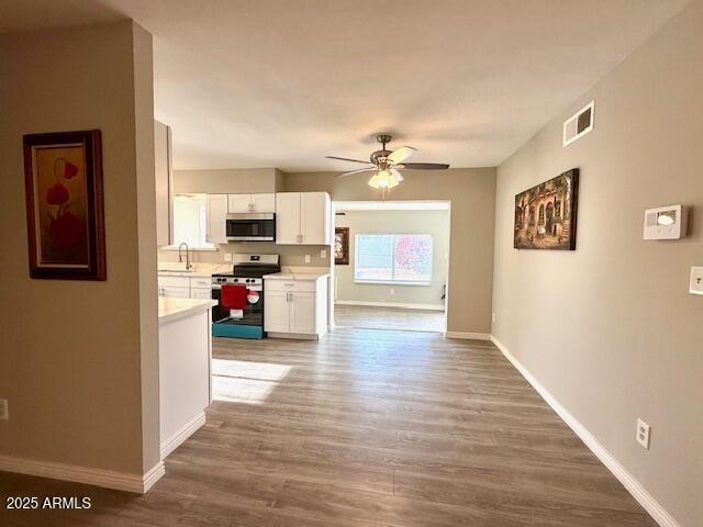 interior space with wood finished floors, visible vents, baseboards, and a sink