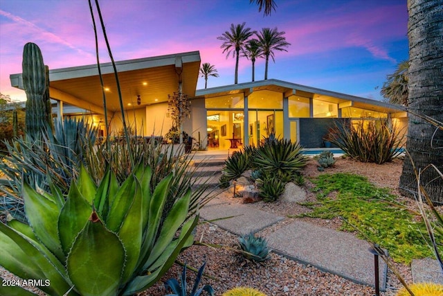 back house at dusk with a patio area