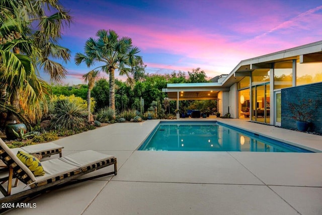 pool at dusk featuring a patio area