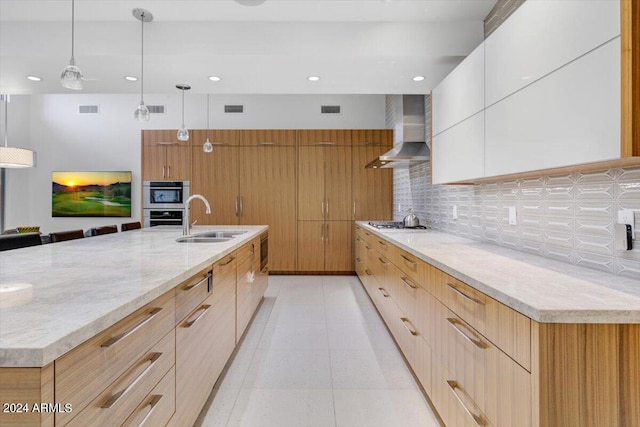 kitchen featuring wall chimney range hood, sink, backsplash, and light stone counters