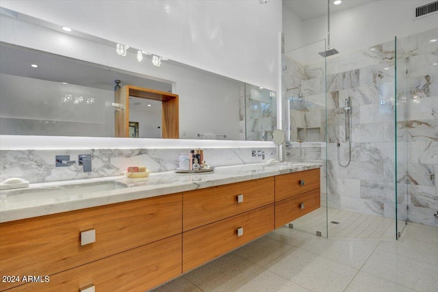 bathroom featuring tile floors, tasteful backsplash, a shower with shower door, and double vanity