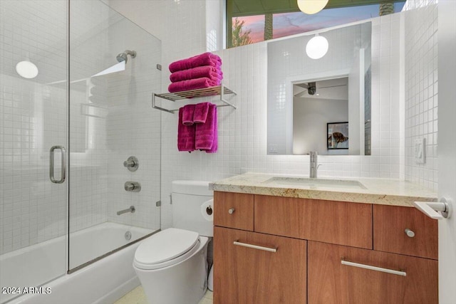 full bathroom with tasteful backsplash, bath / shower combo with glass door, tile walls, toilet, and vanity