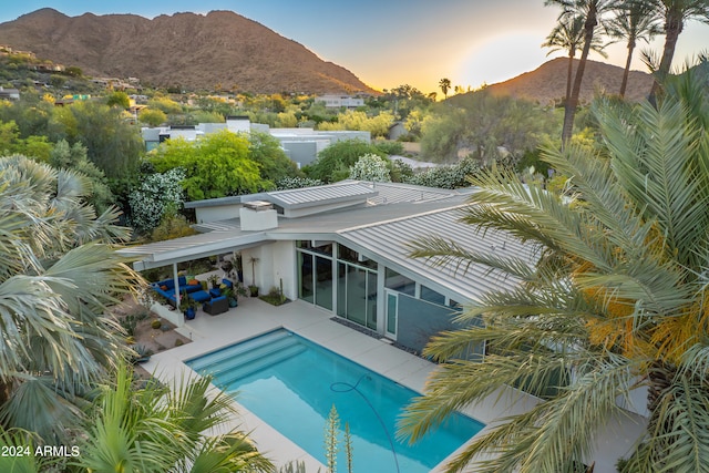 pool at dusk featuring a mountain view and a patio area