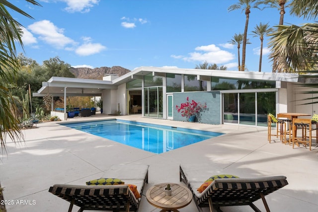 view of pool with an outdoor hangout area, a mountain view, and a patio area