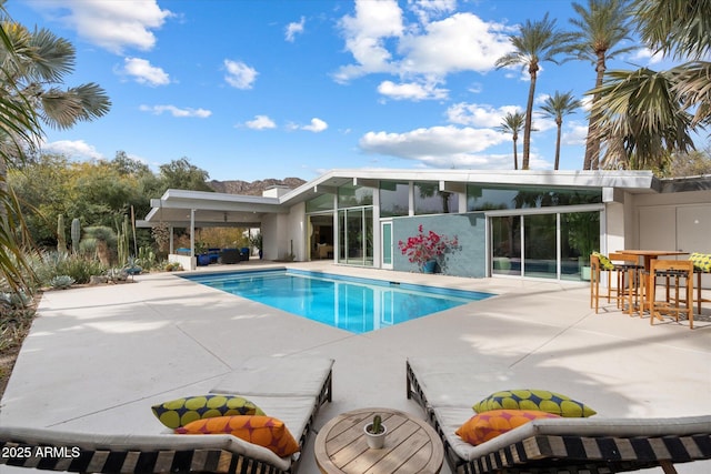 view of swimming pool featuring an outdoor bar and a patio