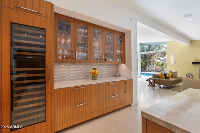 bar with light stone countertops, backsplash, light tile patterned floors, beamed ceiling, and beverage cooler