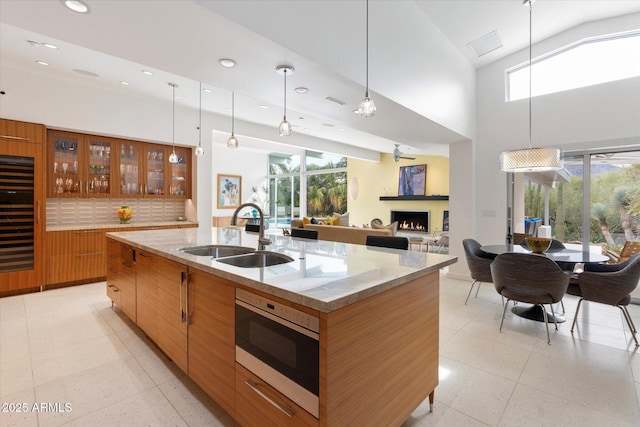 kitchen with decorative light fixtures, sink, a kitchen island with sink, and stainless steel microwave