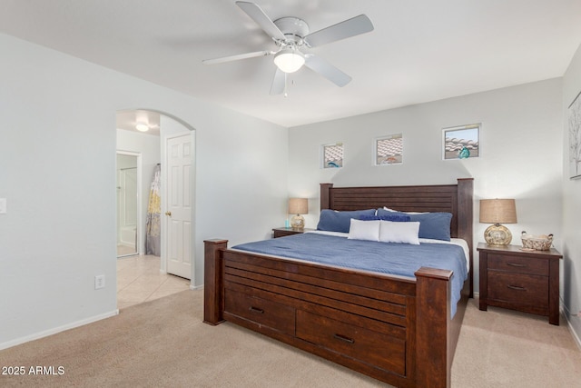 1142 E Mayfield Dr, San Tan Valley, AZ 85143 - bedroom with light colored carpet, arched walkways, baseboards, ensuite bath, and a ceiling fan