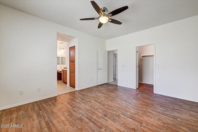 12775 W Lowden Rd, Peoria, AZ 85383 - unfurnished bedroom featuring light wood-style floors, a walk in closet, baseboards, connected bathroom, and ceiling fan
