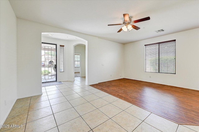 12775 W Lowden Rd, Peoria, AZ 85383 - spare room featuring arched walkways, ceiling fan, light tile patterned floors, and baseboards