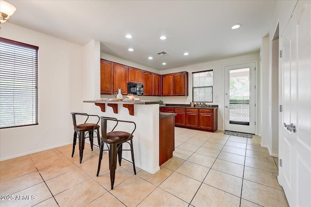 12775 W Lowden Rd, Peoria, AZ 85383 - kitchen with black microwave, a breakfast bar, recessed lighting, light tile patterned flooring, and a peninsula
