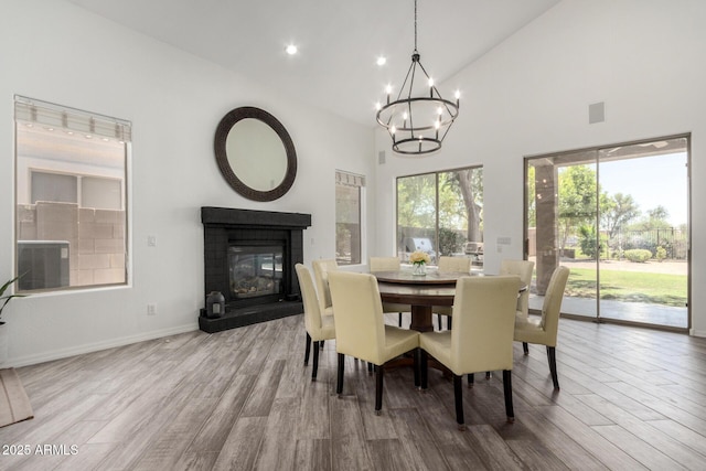 723 E Gemini Pl, Chandler, AZ 85249 - dining area featuring wood finished floors, a glass covered fireplace, a chandelier, high vaulted ceiling, and recessed lighting