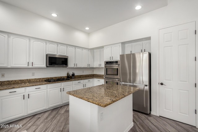 723 E Gemini Pl, Chandler, AZ 85249 - kitchen with appliances with stainless steel finishes, wood finished floors, dark stone counters, white cabinets, and a center island