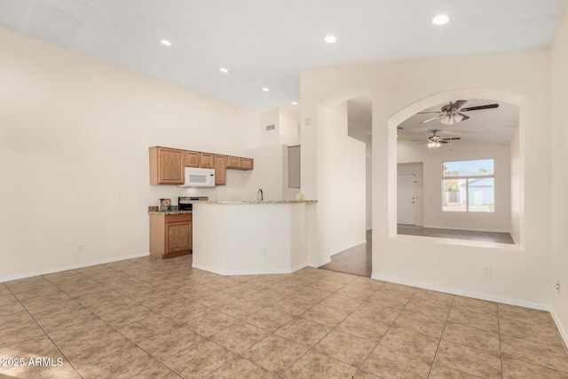 kitchen with ceiling fan, lofted ceiling, stainless steel electric range, light tile patterned floors, and light stone counters