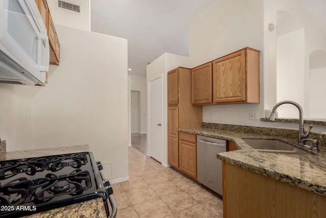 kitchen with dishwasher, sink, black range with gas cooktop, light tile patterned floors, and stone counters