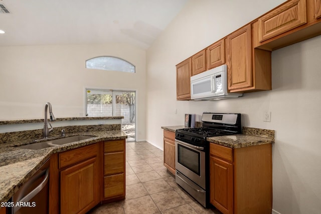 kitchen featuring light tile patterned floors, sink, appliances with stainless steel finishes, and dark stone countertops